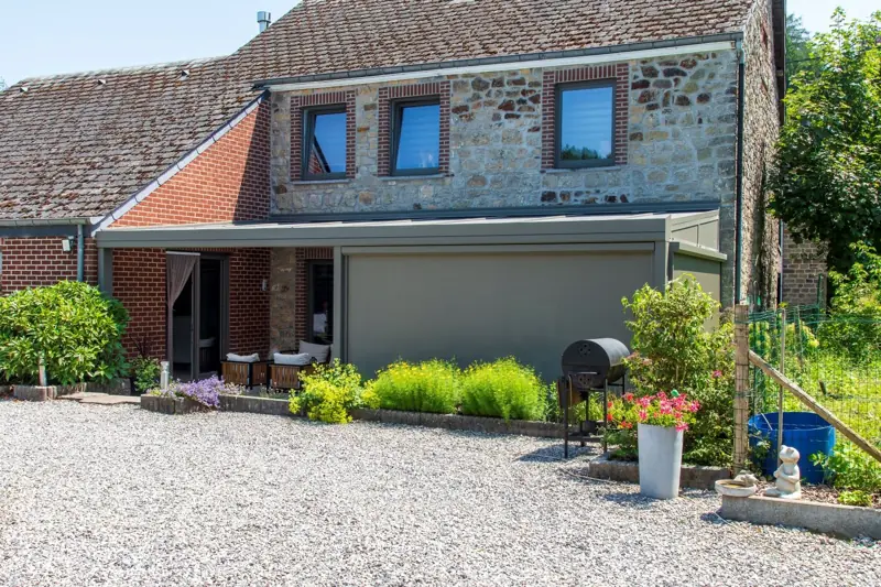 Pergola avec store vertical intégré le long d’une maison en pierre