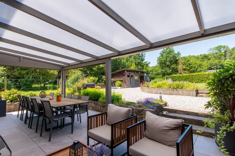 Terrasse couverte par une pergola avec table à manger et salon