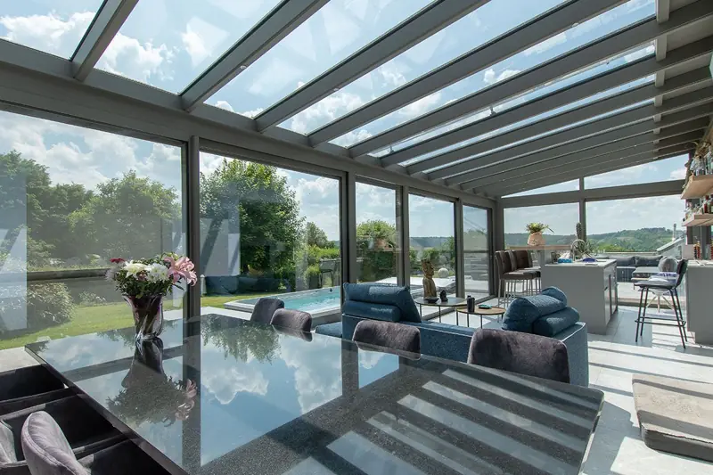 Véranda aluminium lumineuse avec toiture vitrée et vue sur le jardin